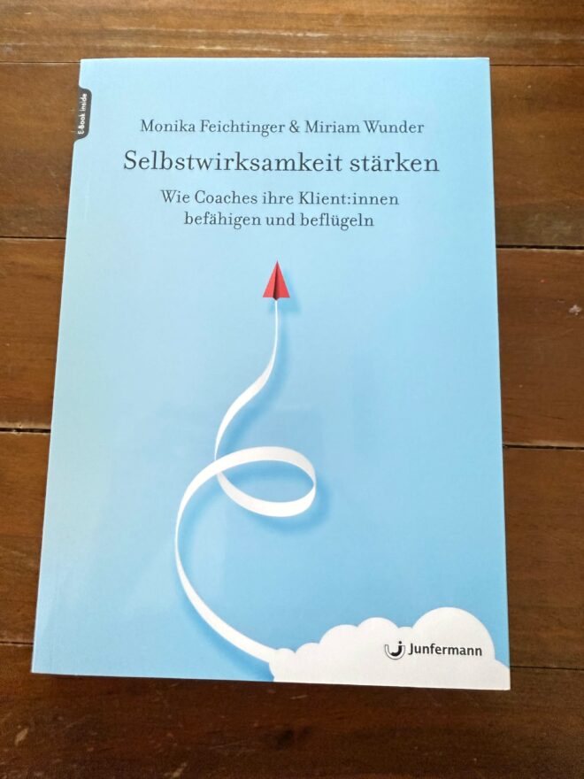 Rezension Selbstwirksamkeit. Das Cover zeigt nach oben geschwungenen Pfeil mit roter Pfeilzpitze.