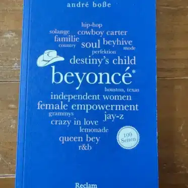 Cover des Buches beyoncé. 100 Seiten von André Boße, erschienen im Reclam Verlag, auf Holztisch fotografiert