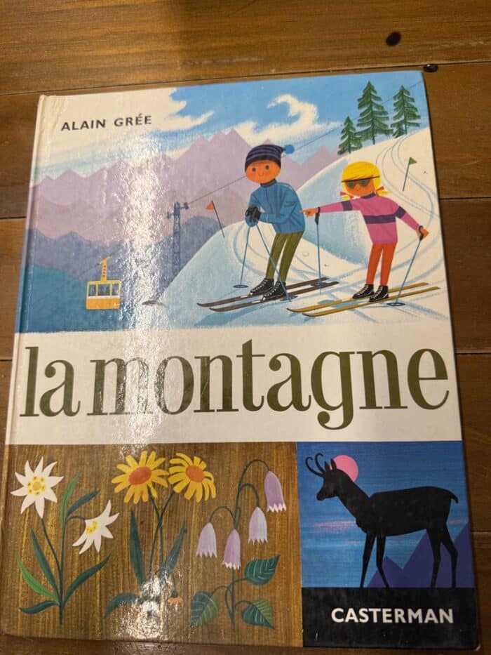 Cover von La montagne: zwei Kinder auf Skiern mit gelber Seilbahn, darunter Bergblumen und eine Gämse