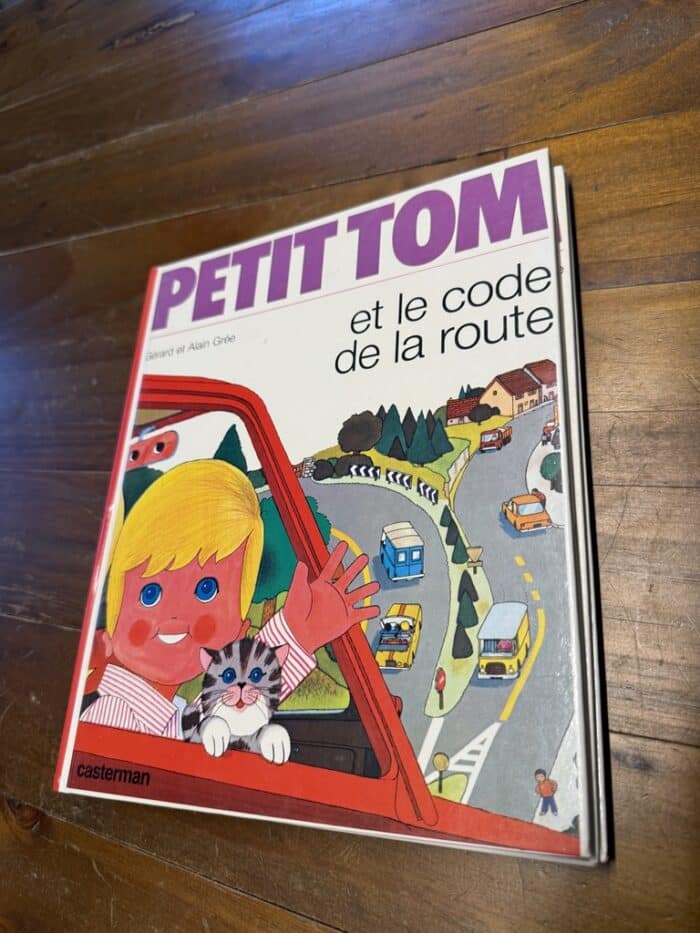 Cover von Petit Tom et le code de la route: Junge winkt mit einer Katze aus einem roten Auto, dahinter eine kurvige Straße
