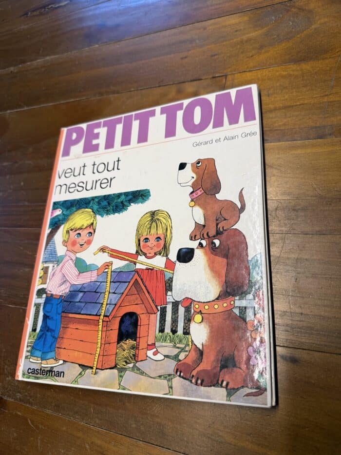Cover von Petit Tom veut tout mesurer: Zwei Kinder messen eine Hundehütte, daneben ein großer und ein kleiner Hund